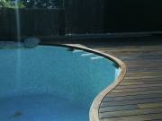 Tarima para exterior en calidad Ipe Grapa Oculta con coronamiento de piscina en curva.